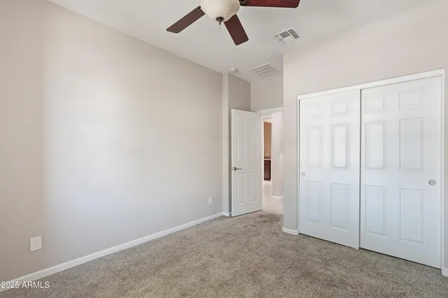 an empty room with a ceiling fan and carpet