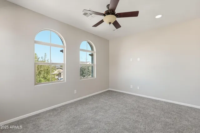 an empty room with windows and ceiling fan