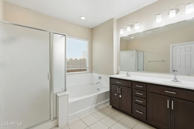 a spacious bathroom with a double vanity sink a mirror and a bathtub
