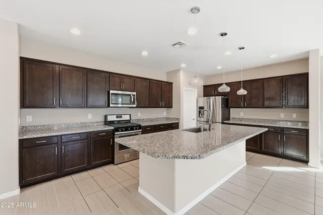a large kitchen with stainless steel appliances granite countertop a sink stove and refrigerator