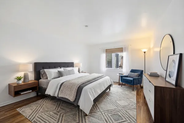 a bedroom with a bed wooden floor and a rug