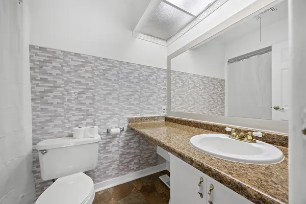 a bathroom with a granite countertop sink a toilet and a mirror