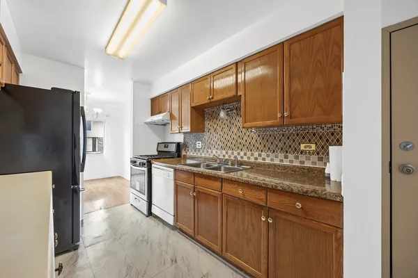 a kitchen with stainless steel appliances granite countertop a refrigerator a stove and a sink