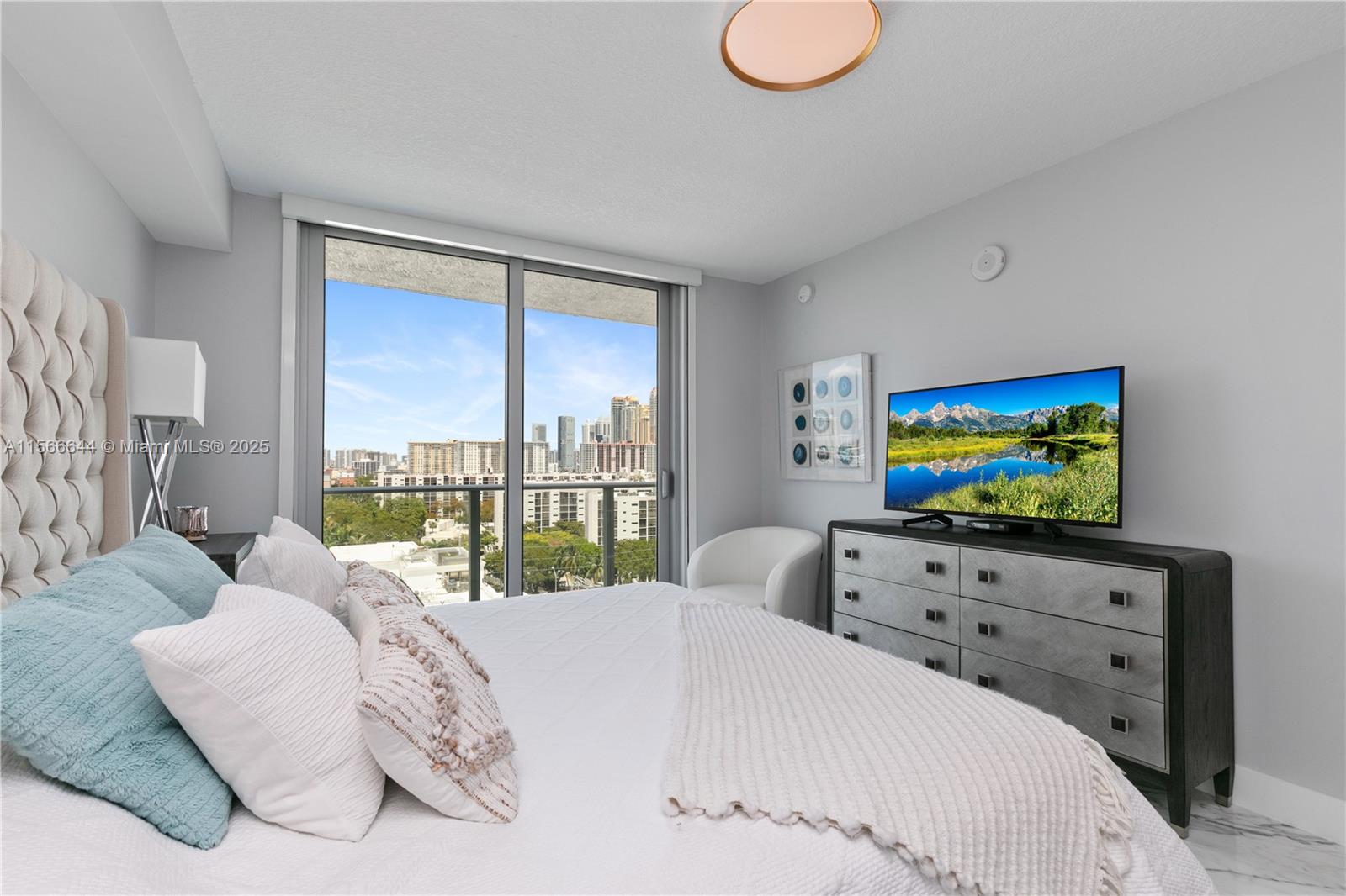 330 Sunny Isles Boulevard, Unit 51103 Sunny Isles Beach, FL 33160 - Photo 17 of 34 a bedroom with a bed and a flat tv screen next to a window