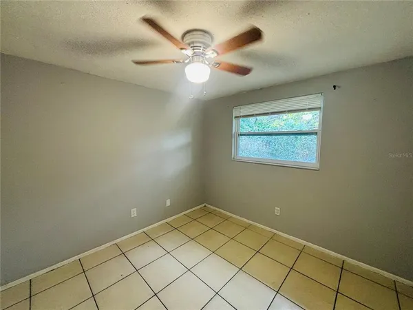 an empty room with a chandelier fan and windows