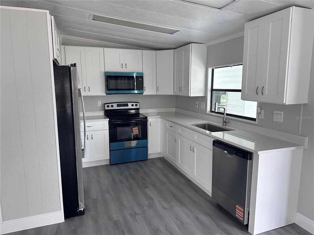 3458 North Citrus Circle, Unit 1803 Zellwood, FL 32798 - Photo 7 of 20 a kitchen with stainless steel appliances granite countertop white cabinets a sink a stove a refrigerator and a microwave