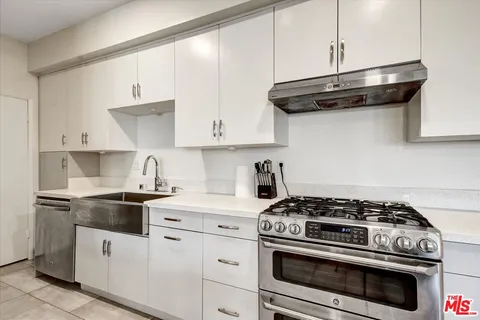 a kitchen with stainless steel appliances granite countertop white cabinets a stove a sink and dishwasher