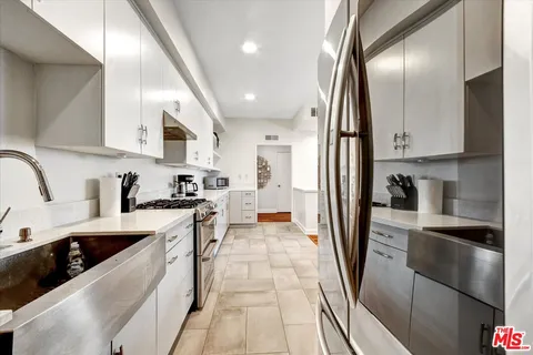 a kitchen with stainless steel appliances granite countertop a refrigerator a sink a stove and white cabinets