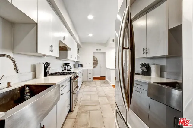 a kitchen with stainless steel appliances granite countertop a refrigerator a sink a stove and white cabinets