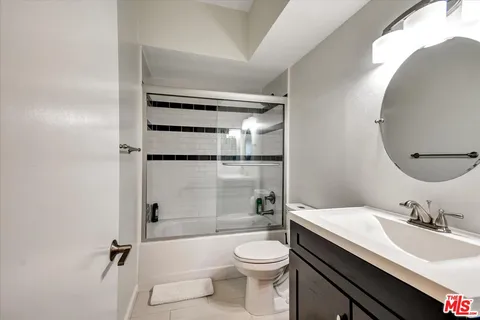 a bathroom with a granite countertop sink toilet mirror and shower