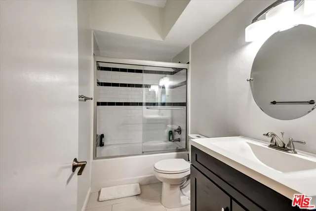 a bathroom with a granite countertop sink toilet mirror and shower