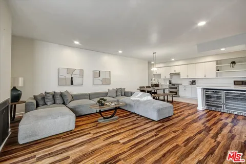 a living room with furniture kitchen view and a wooden floor