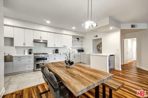 a kitchen with stainless steel appliances granite countertop a stove refrigerator a sink dishwasher a dining table and chairs with wooden floor