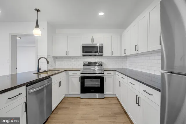 a kitchen with granite countertop white cabinets and stainless steel appliances