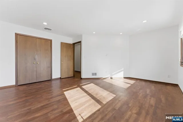 a view of an empty room with wooden floor and closet