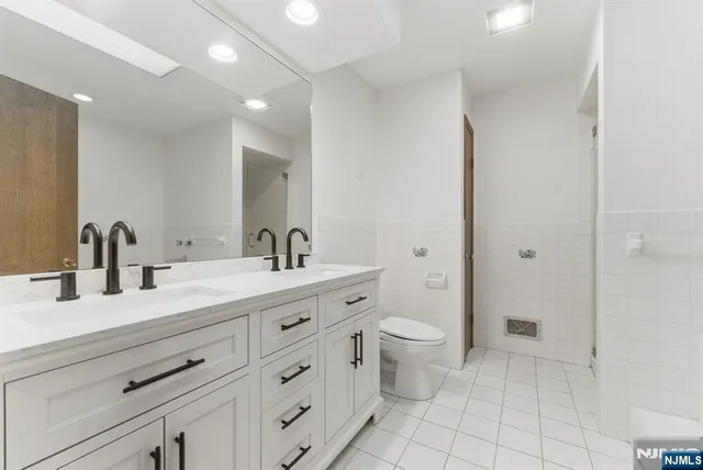 a spacious bathroom with a double vanity sink a toilet and a mirror