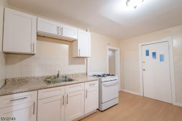 a kitchen with granite countertop a sink cabinets and stainless steel appliances