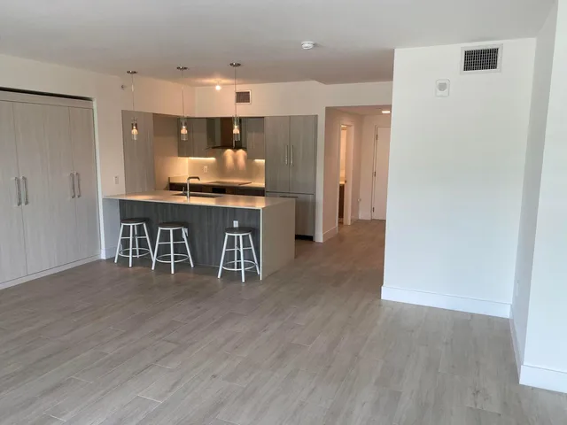 a kitchen with stainless steel appliances a kitchen island hardwood floor and a sink