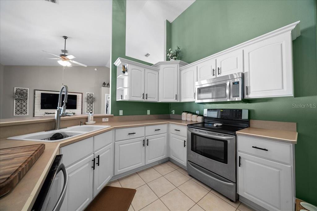 10080 Southeast 69th Terrace Belleview, FL 34420 - Photo 17 of 51 a kitchen with white cabinets and appliances