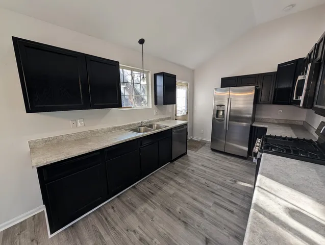 a kitchen with stainless steel appliances kitchen island granite countertop a refrigerator a sink and a stove