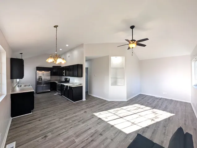 a open kitchen with a sink and dishwasher a stove top oven with wooden floor