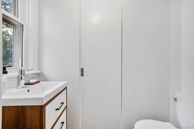 a bathroom with a sink vanity mirror and toilet