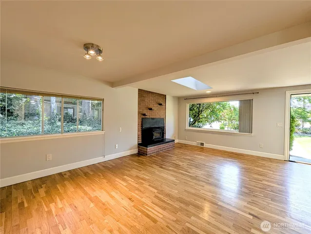 an empty room with large windows and a fireplace