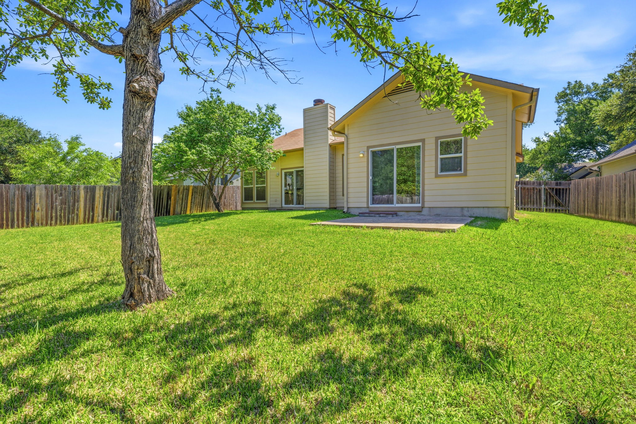 14818 Yellowleaf Trail Austin, TX 78728 - Photo 19 of 26 Expansive fenced backyard featuring a large green lawn, mature tree, and a concrete patio