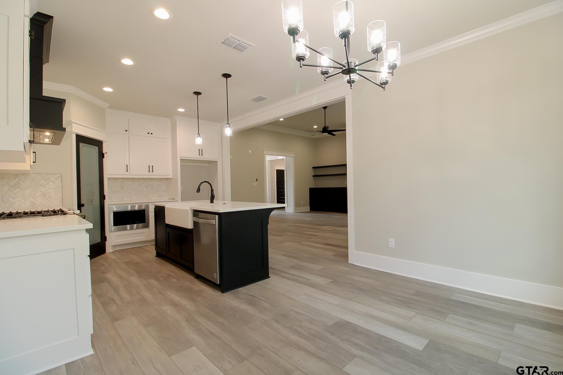 1069 Stagecoach Bend Bullard, TX 75757 - Photo 12 of 44 a large room with kitchen island a refrigerator a sink dishwasher a dining table and chairs with wooden floor