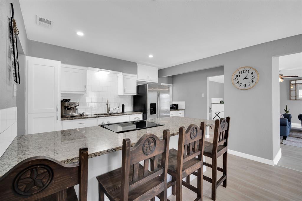 a kitchen with stainless steel appliances granite countertop a stove top oven a sink a table and chairs