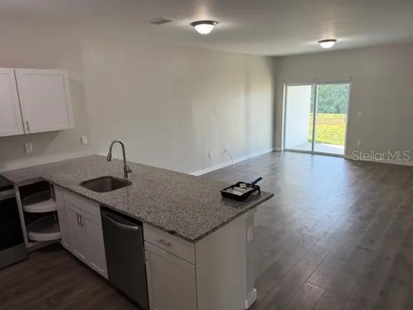a kitchen with granite countertop a sink a stove and cabinets