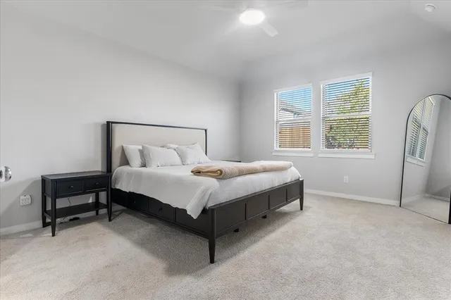 a bed sitting in a bedroom next to a window and a chair