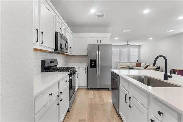 a kitchen with stainless steel appliances granite countertop a white stove top oven a sink and dishwasher with wooden floor