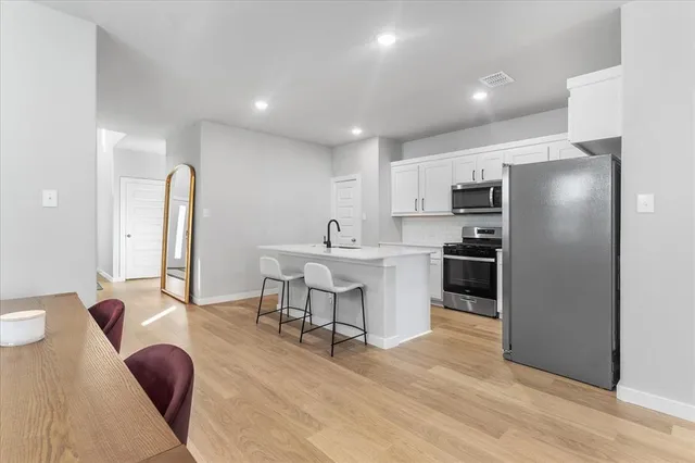 a living room with stainless steel appliances furniture a dining table and kitchen view
