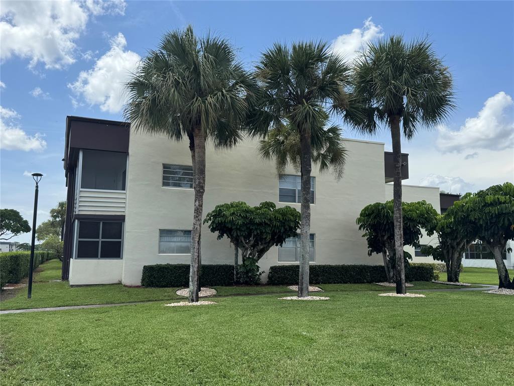 768 P Normandy, Unit 768 Delray Beach, FL 33484 - Photo 17 of 34 front view of a house with a yard and palm trees