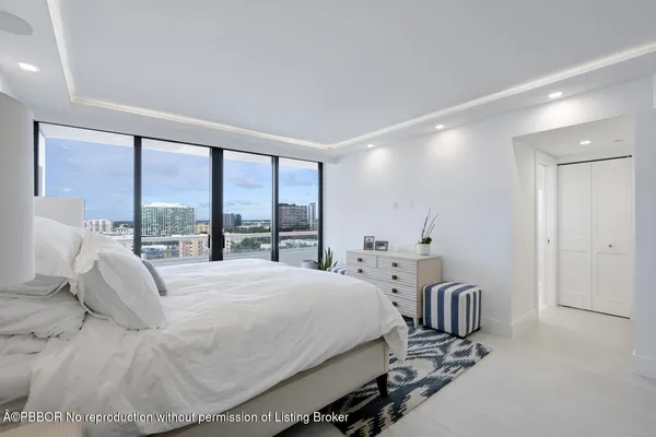 a bedroom with a bed a table and large windows