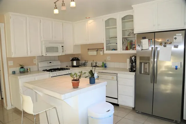 a kitchen with stainless steel appliances a refrigerator sink and white cabinets