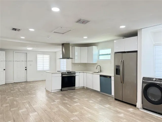 a large kitchen with stainless steel appliances granite countertop a refrigerator and a stove top oven