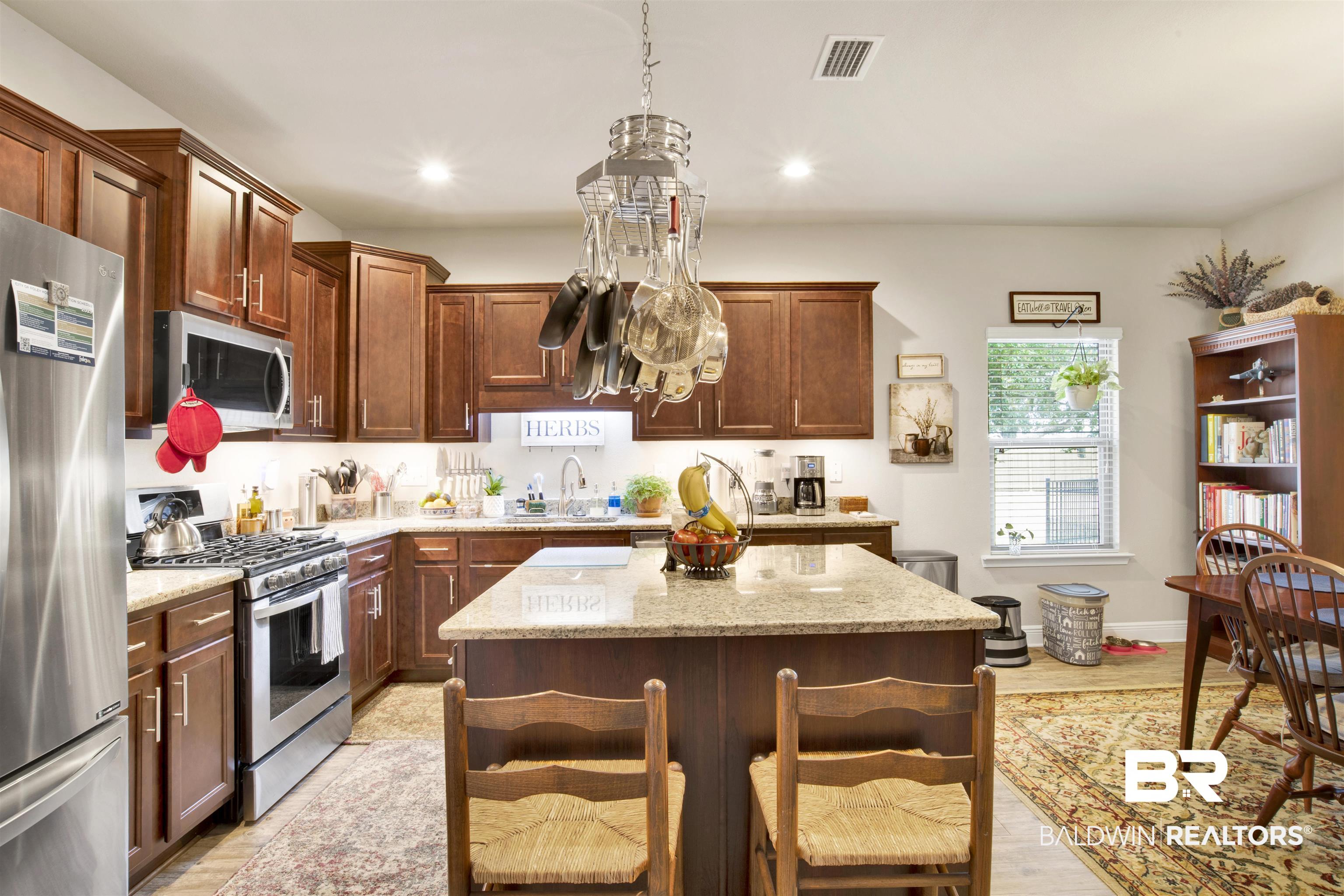 1476 Surrey Loop Foley, AL 36535 - Photo 9 of 31 Kitchen featuring a breakfast bar, stainless steel appliances, a center island, light stone countertops, and decorative light fixtures