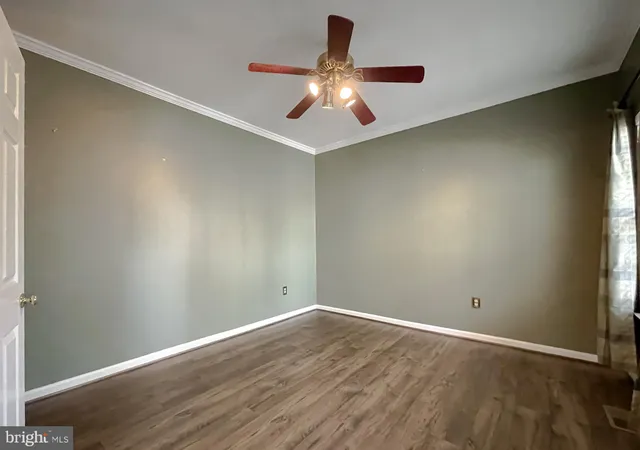 a view of an empty room with chandelier fan and fire place