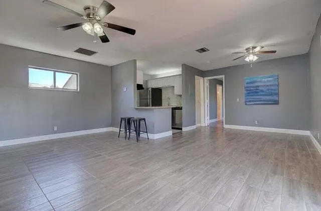 a view of a livingroom with a dining table & a chandelier fan