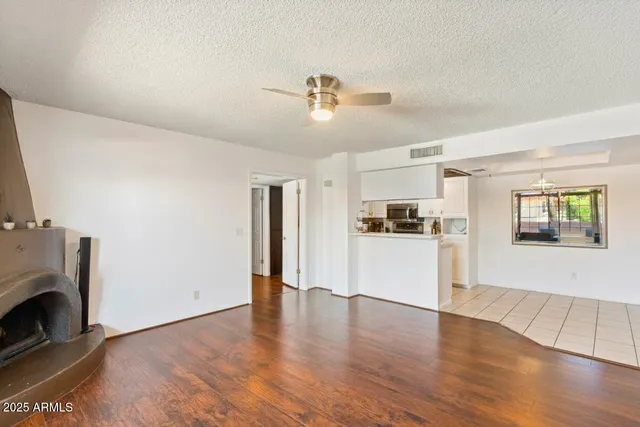 a view of a kitchen and an empty room with wooden floor