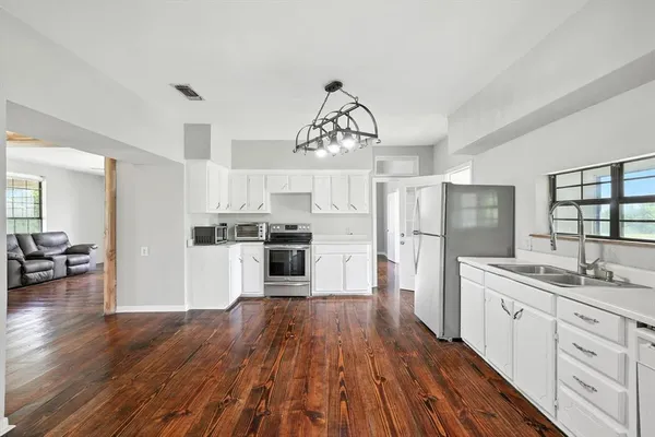 a kitchen with a refrigerator a sink dishwasher a stove and white cabinets with wooden floor