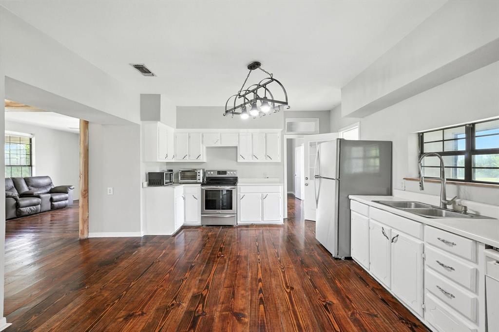 400 Katy Street Alba, TX 75410 - Photo 16 of 40 a kitchen with a refrigerator a sink dishwasher a stove and white cabinets with wooden floor