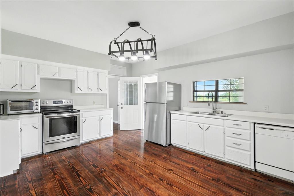 400 Katy Street Alba, TX 75410 - Photo 18 of 40 a kitchen with stainless steel appliances a stove a sink dishwasher a refrigerator and white cabinets with wooden floor