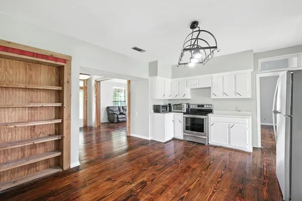 a kitchen with wooden floors and white cabinets