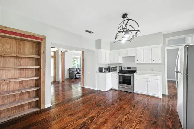 a kitchen with wooden floors and white cabinets