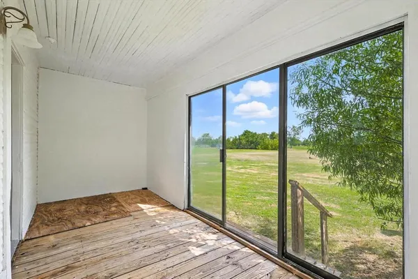 a view of empty room with wooden floor and floor to ceiling window