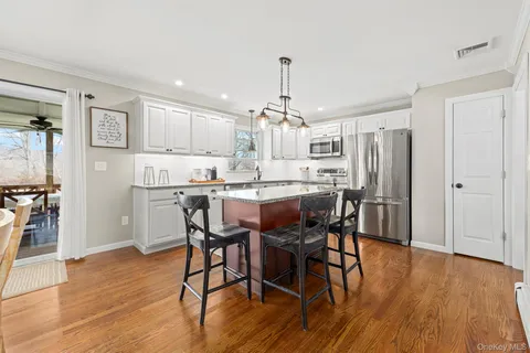 a kitchen with stainless steel appliances a dining table chairs refrigerator and cabinets