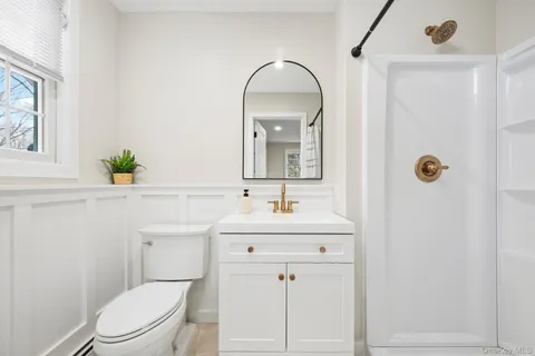 a bathroom with a toilet a sink a mirror and vanity